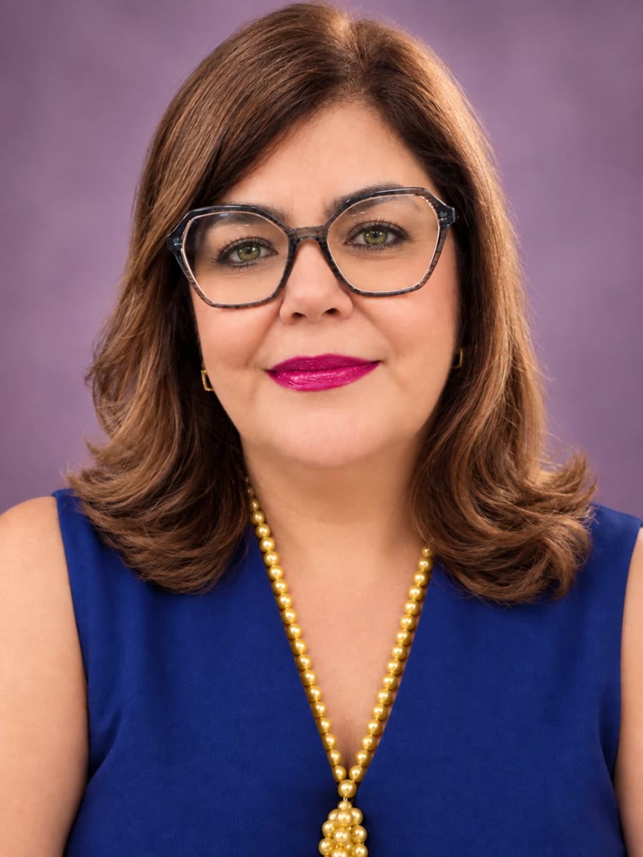 Miriam Mariano com blusa azul e colar dourado, olhar acolhedor