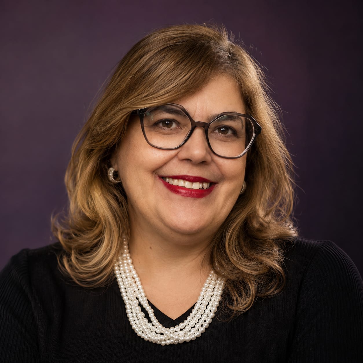 Miriam Mariano sorrindo, com blusa preta e colar de pérolas
